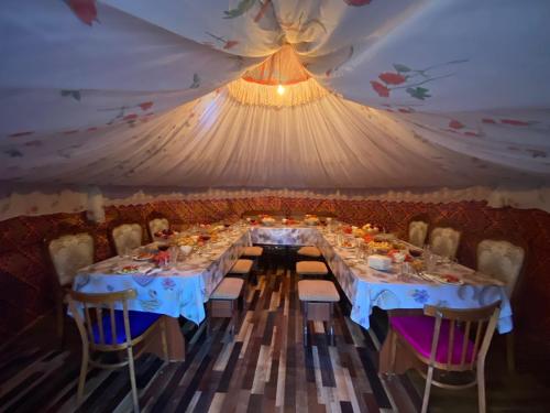 une salle à manger avec des tables et des chaises dans une tente dans l'établissement Guesthouse Damira, à Kyzyloy