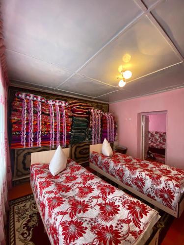 a bedroom with two beds and a wall with curtains at Guesthouse Damira in Kyzyloy