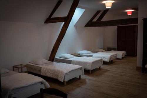 een kamer met 4 bedden in een kamer met balken bij gîte du château in La Bussière