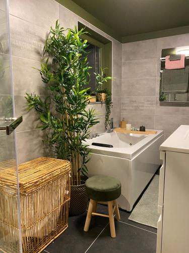a bathroom with a tub and a stool and plants at Maisonnette Les garages in Namur