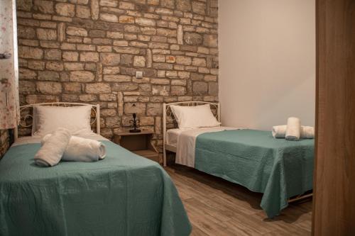 a room with two beds and a brick wall at Το πέτρινο της Έυας in Ellinoekklisía