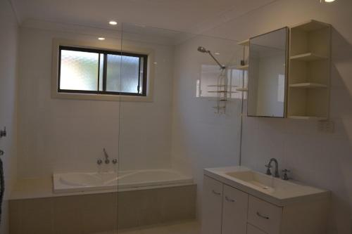 La salle de bains est pourvue d'une baignoire, d'un lavabo et d'une douche. dans l'établissement Barefoot Bungalow, à Hat Head