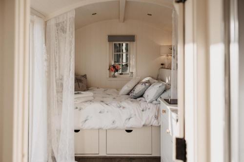 Schlafzimmer mit einem großen Bett und einem Fenster in der Unterkunft The Dragonfly Shepherds Hut in Colchester