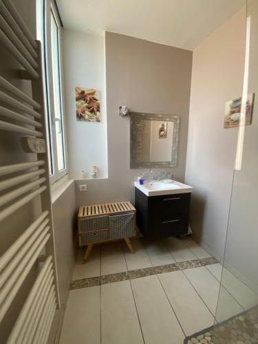 une salle de bain avec un lavabo et un miroir dans l'établissement city loft parking privé gratuit, à Étretat