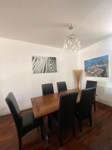 une salle à manger avec une table en bois et des chaises noires dans l'établissement city loft parking privé gratuit, à Étretat