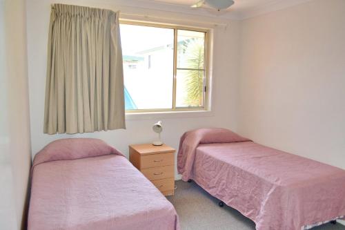 two beds in a room with a window at Beach Retreat in South West Rocks