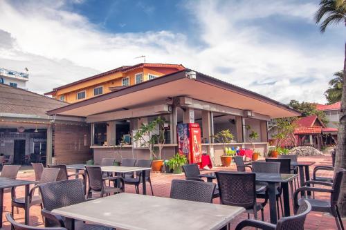 a patio with tables and chairs in front of a building at Sandy Beach Resort By Casa Loma in Pantai Cenang