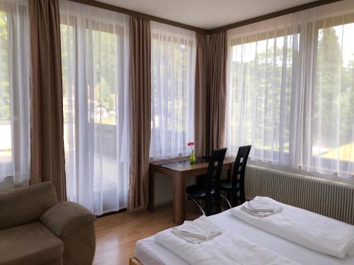 a hotel room with two beds and a table and windows at Sporthotel am Ötscher in Lackenhof