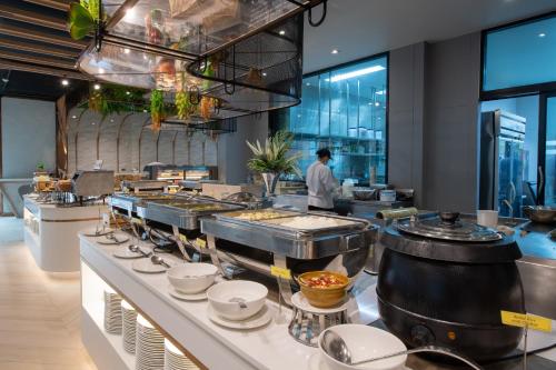 Pattaya Discovery Beach Hotel - SHA Extra Plus في باتايا سنترال: مطبخ مع شيف يحضر الطعام في مطعم