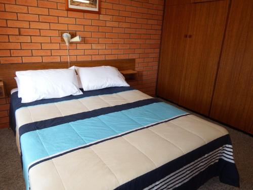 a bed in a bedroom with a brick wall at Cameo Court Unit 7 South West Rocks in South West Rocks