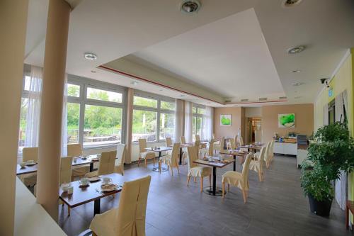 un restaurante con mesas, sillas y ventanas en Green Business Hotel am Mühlengrund Graz en Graz