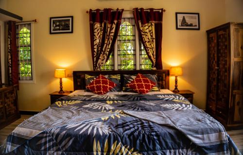 a bedroom with a large bed with two windows at The Mahizh Home in Mahabalipuram