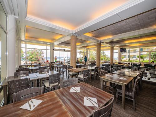 a restaurant with wooden tables and chairs and windows at Vila Baleira Suites in Porto Santo
