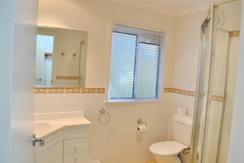 a bathroom with a toilet and a sink and a mirror at Hughs Hideaway Arakoon in Arakoon