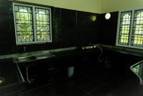 a black bathroom with a sink and two windows at The Mahizh Home in Mahabalipuram