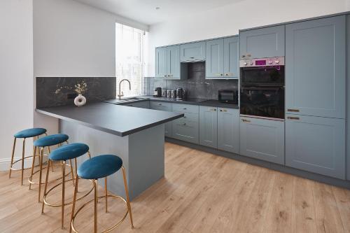eine Küche mit blauen Schränken und eine Insel mit blauen Stühlen in der Unterkunft Host & Stay - Parkside Villa in Harrogate