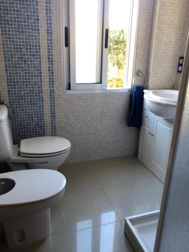 a bathroom with a toilet and a sink and a window at APARTAMENTO KORINTO in Benicàssim