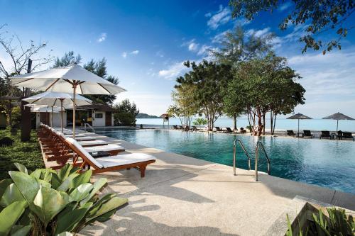 Centara Chaan Talay Resort And Villas Trat في Ban Khlong Muang: مسبح فيه كراسي ومظلات بجانب الماء