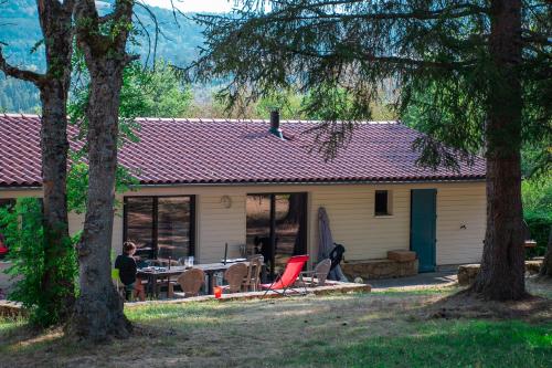 Un uomo seduto a un tavolo di fronte a una casa di Village de gîtes de la Forêt de Ganigal a Le Malzieu-Ville