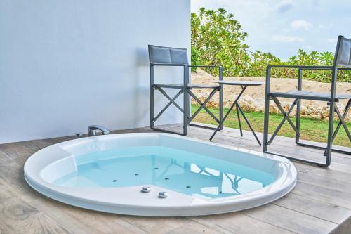 una vasca da bagno con 2 sedie, situata su un pavimento in legno di Watermark Hotel & Resorts Okinawa Miyakojima a Miyakojima