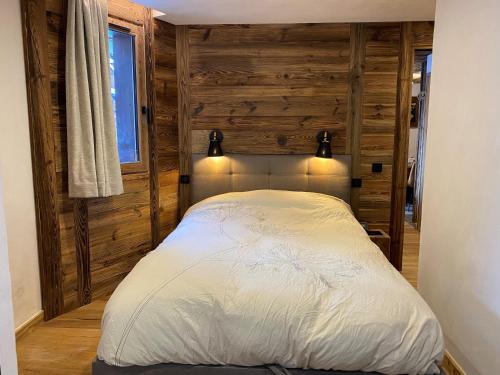 ein Schlafzimmer mit einem Bett in einem Zimmer mit Holzwänden in der Unterkunft les jardins de val in Val dʼIsère