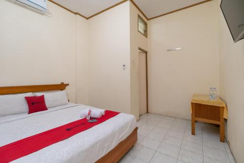 a bedroom with a bed with a red blanket and a desk at RedDoorz near RS Awal Bros Sudirman Pekanbaru in Parit