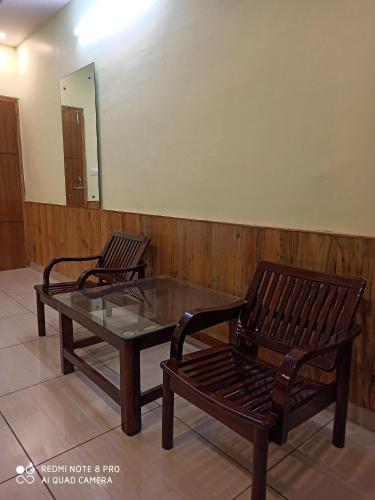 Duas cadeiras, uma mesa de vidro e um espelho. em CHAMAN BASERA em Shamshi