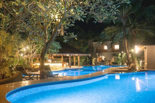 a pool at night with chairs and trees at Coconut Lodge Resort in Jepara