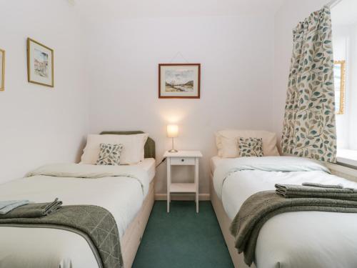 Habitación con 2 camas y mesa con lámpara. en Ty Twmp Tump Cottage en Brecon