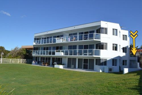 a white apartment building with a large yard at Ocean Shores Apartment 13 in South West Rocks
