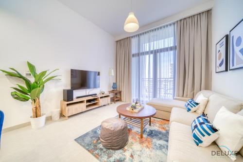 a living room with a couch and a tv at Sophisticated 1BR at Town Square Rawda Dubailand by Deluxe Holiday Homes in Dubai