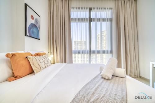 a bedroom with a large white bed with a large window at Sophisticated 1BR at Town Square Rawda Dubailand by Deluxe Holiday Homes in Dubai