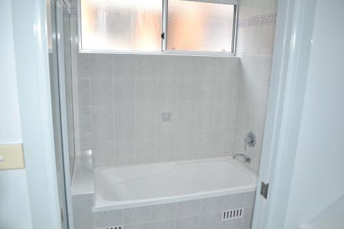 Un baño con bañera y ventana. en Ocean Shores Apartment 14 - Bring your own linen., en South West Rocks