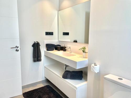 La salle de bains blanche est pourvue d'un lavabo et d'un miroir. dans l'établissement Penthouse in exclusive resort, à Estepona