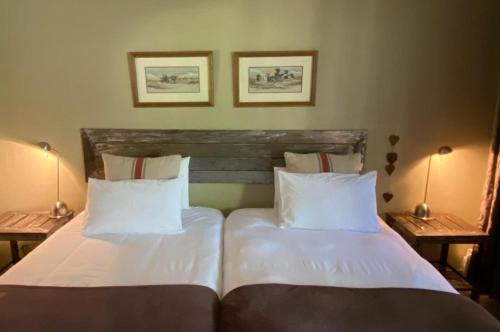 a bedroom with two beds with white sheets and two lamps at Olive Leaves Guest House in Gaborone