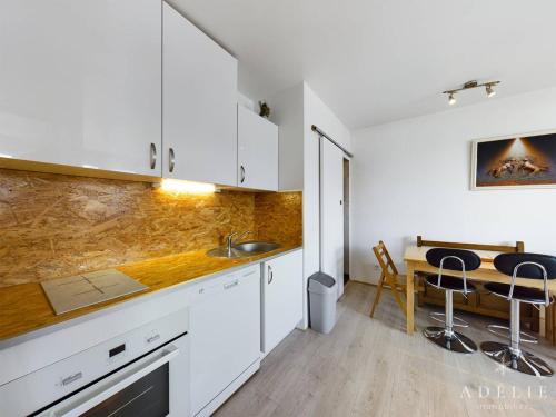 - une cuisine avec des placards blancs et une table à manger dans l'établissement Appartement moderne 5 pers, skis aux pieds, parking inclus - FR-1-398-567, à La Rosière