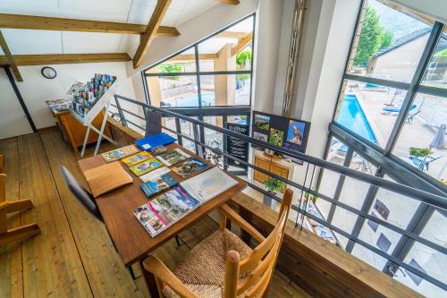 een eetkamer met een tafel en een aantal ramen bij Village de gîtes de Blajoux in Quézac