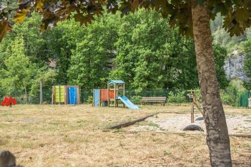 un parque infantil con un tobogán y un banco en un parque en Village de gîtes de Blajoux, en Quézac