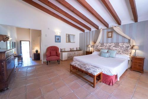 Hotel Rural S'Olivaret & Spa في ألارو: غرفة نوم بسرير ابيض وكرسي احمر