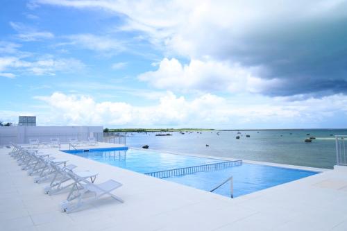 a swimming pool with chairs and a view of the ocean at Watermark Hotel Okinawa Miyakojima in Miyako-jima