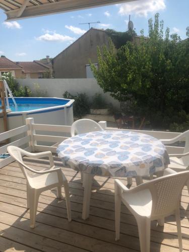 - une table et des chaises sur une terrasse avec piscine dans l'établissement Les Amandiers, à Abeilhan