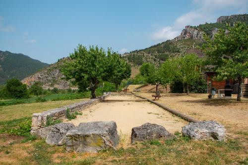 a field with some rocks and trees and a mountain at Village de gîtes de Blajoux in Quézac