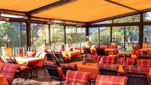 een restaurant met tafels en stoelen in een kamer met ramen bij Café Pension Alpina in Innsbruck