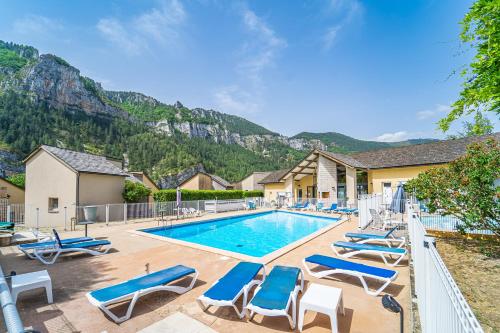 a swimming pool with lounge chairs and a mountain at Village de gîtes de Blajoux in Quézac