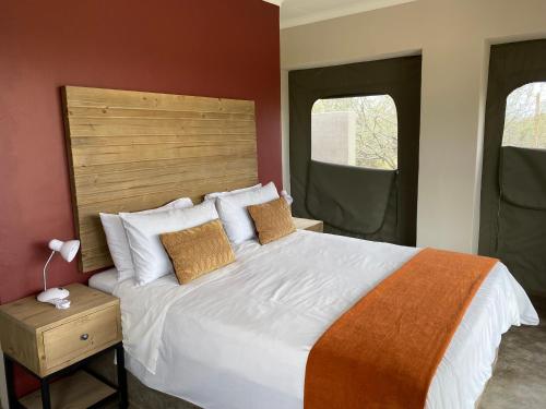 a bedroom with a large bed and two windows at Sunset Lodge & Safaris in Guernsey Nature Reserve