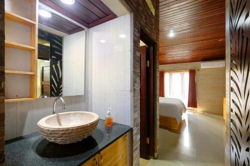 uma casa de banho com um lavatório e uma cama num quarto em Jero Delod Kedungu em Tabanan