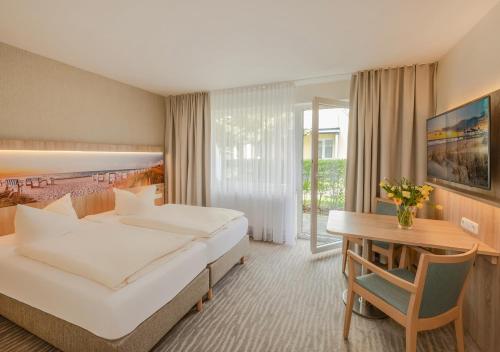 a hotel room with a bed and a table at Haus Schwalbe mit Vineta Komfort Häusern in Zempin