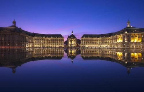 un edificio con luci in acqua di notte di Le Manhattan 3*, Lumineux , calme vue sur le lac a Bruges