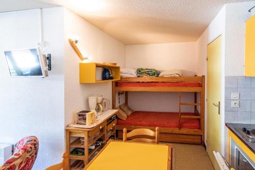 ein kleines Zimmer mit einem Etagenbett und einem Tisch in der Unterkunft Appartement Chabrières in Réallon