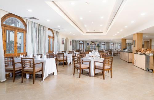 a restaurant with white tables and wooden chairs at Safir Dahab Resort in Dahab